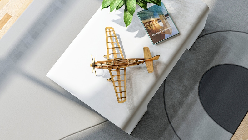 May include: A wooden model airplane on a white surface with a book titled "Travel Guide" on top of the surface.