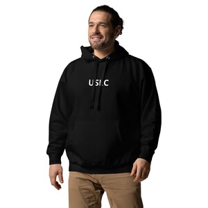 Puede incluir: Sudadera con capucha negra con un logotipo "U.S.I.C." blanco en la parte delantera.