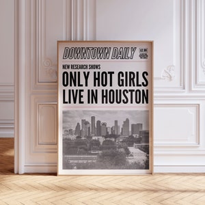May include: A framed poster with the headline "ONLY HOT GIRLS LIVE IN HOUSTON" in bold black letters. The poster also features the text "DOWNTOWN DAILY" and a grayscale image of the Houston skyline. The frame is a light brown color.