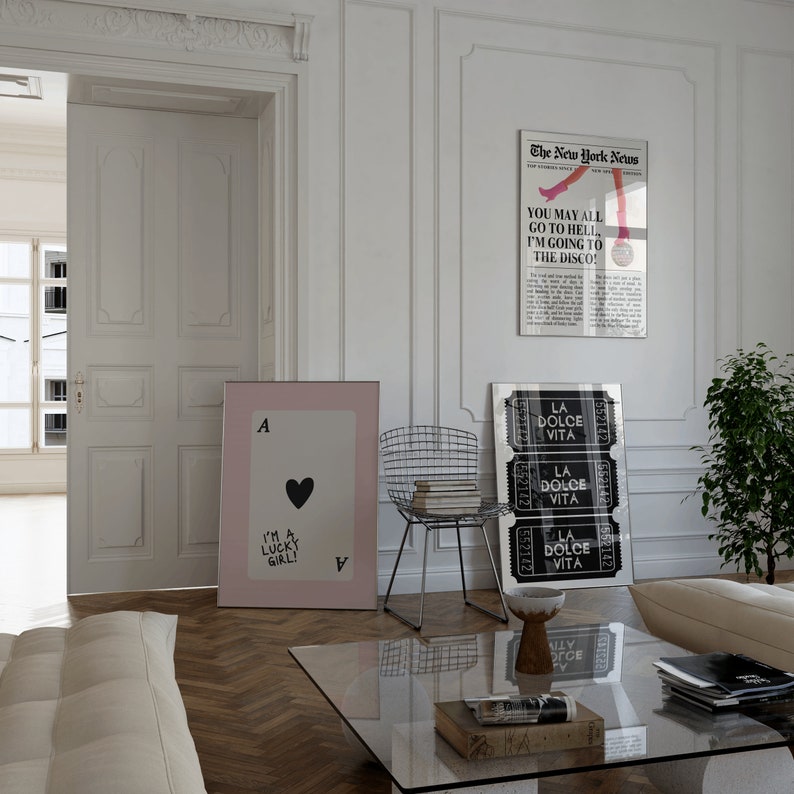 Puede incluir: Un interior de sala de estar con un sof&aacute; blanco, una mesa de caf&eacute; de vidrio y tres impresiones enmarcadas en la pared. Las impresiones muestran una carta de juego, un art&iacute;culo de peri&oacute;dico con el texto "You may all go to hell, I'm going to the disco!" y una impresi&oacute;n en blanco y negro con el texto "La Dolce Vita" repetido tres veces.