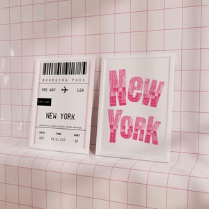 Pode incluir: Duas impress&otilde;es emolduradas brancas em uma parede de azulejos rosa. A impress&atilde;o da esquerda &eacute; um cart&atilde;o de embarque para um voo para Nova York, com o texto "BOARDING PASS", "ONE WAY", "LGA", "FIRST CLASS", "NEW YORK", "GATE 422", "TIME 01:11 EST", e "SEAT 18". A impress&atilde;o da direita tem a palavra "New York" em letras grandes de cor rosa.