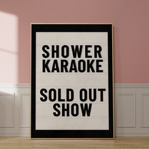 以下が含まれることがあります： 白い背景に黒い文字で「Shower Karaoke Sold Out Show」と書かれた、黒い枠の看板です。