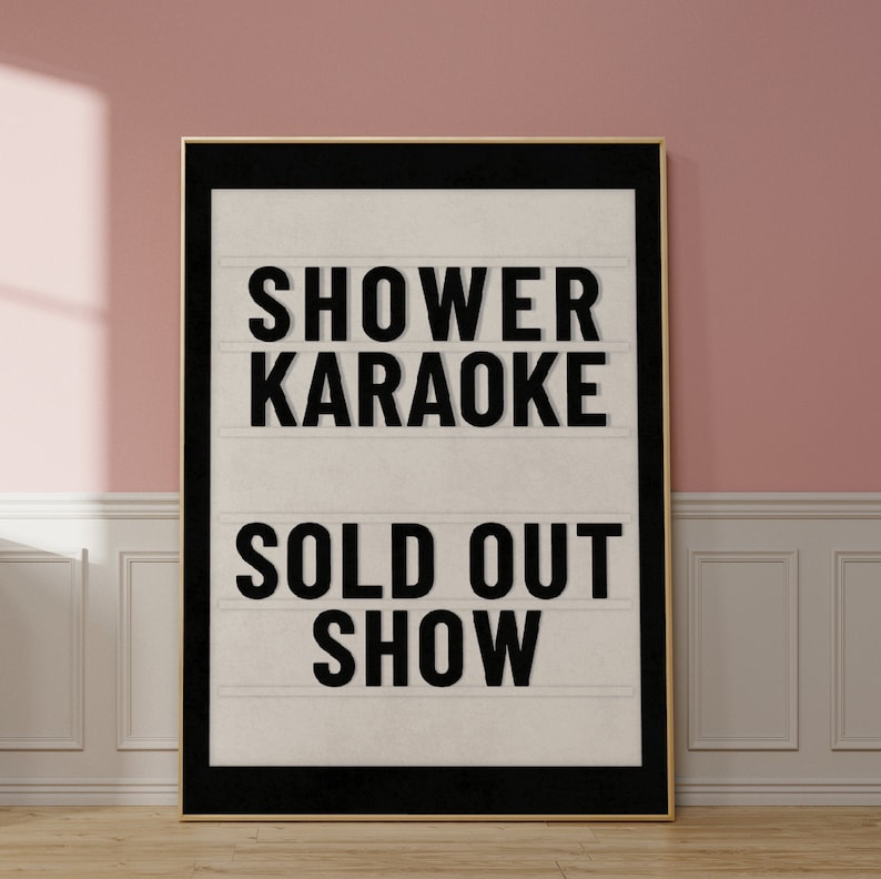 以下が含まれることがあります： 白い背景に黒い文字で「Shower Karaoke Sold Out Show」と書かれた、黒い枠の看板です。