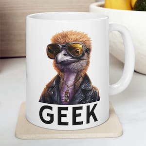 Puede incluir: Taza de cerámica blanca con un gráfico de una avestruz con gafas de sol y una chaqueta de cuero. El texto "GEEK" está impreso en negro debajo de la imagen.