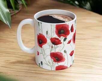 May include: White ceramic mug with a red poppy flower pattern. The mug is filled with coffee.
