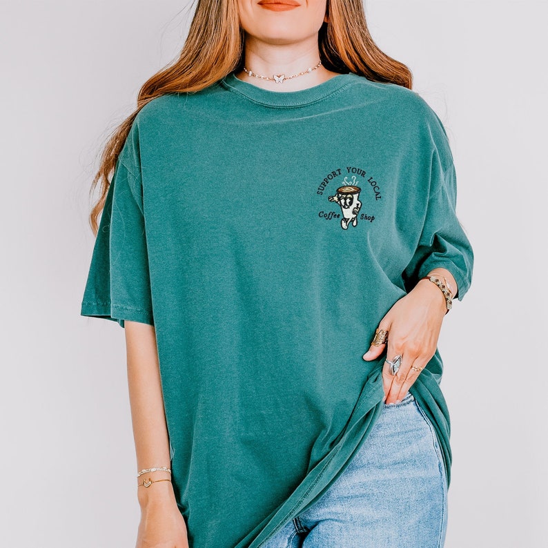 May include: Teal blue t-shirt with a graphic of a coffee cup and the text "Support Your Local Coffee Shop".
