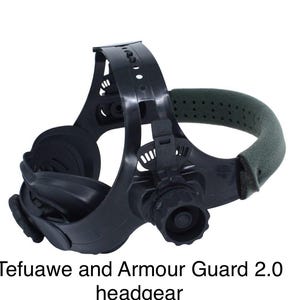 May include: Black welding headgear with a green padded head support. The headgear has adjustable straps and a large lens area. The text "Tefuawe and Armour Guard 2.0 headgear" is printed at the bottom of the image.