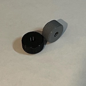 May include: Two small, round, textured wheels. One wheel is black and the other is grey.