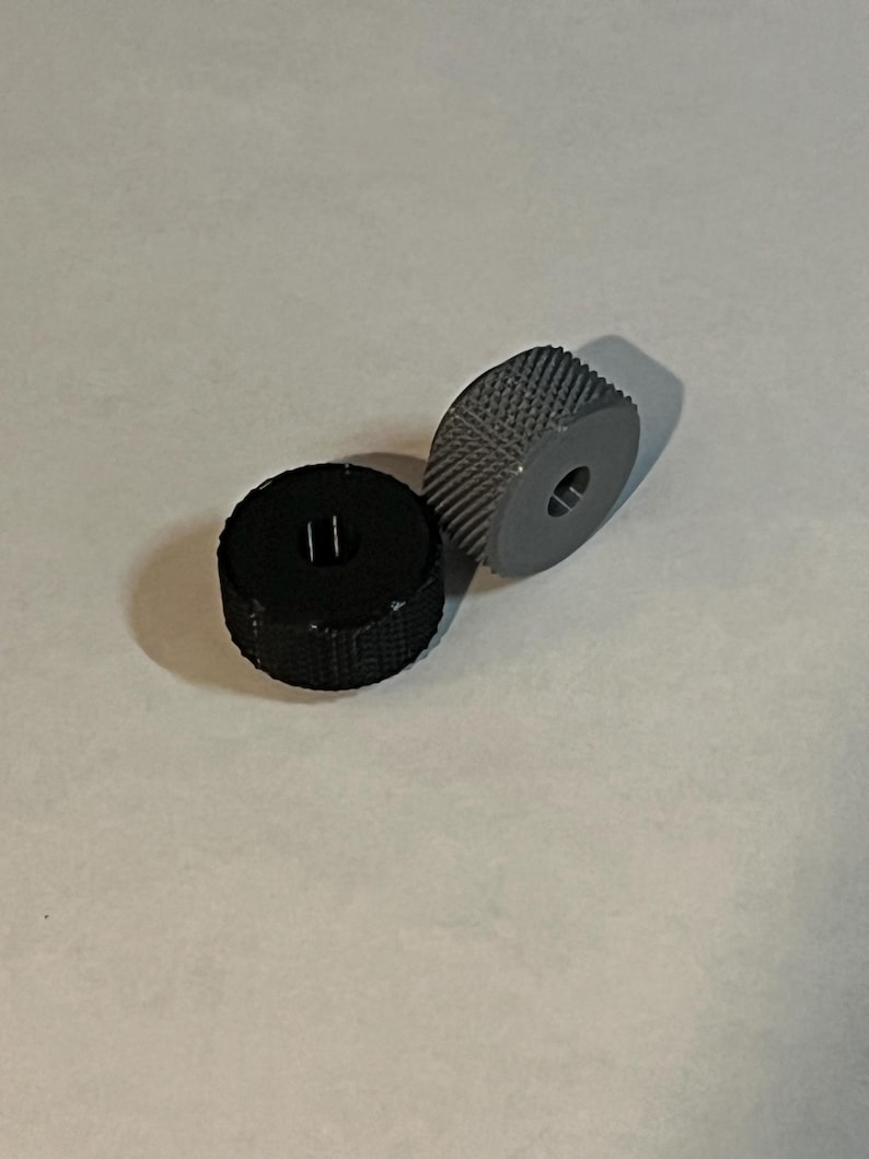 May include: Two small, round, textured wheels. One wheel is black and the other is grey.