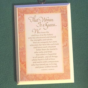 May include: A rectangular wall plaque with a white frame and a decorative marbled border in shades of peach and cream. The plaque features a printed poem in elegant script, with a small metal ring at the top for hanging.