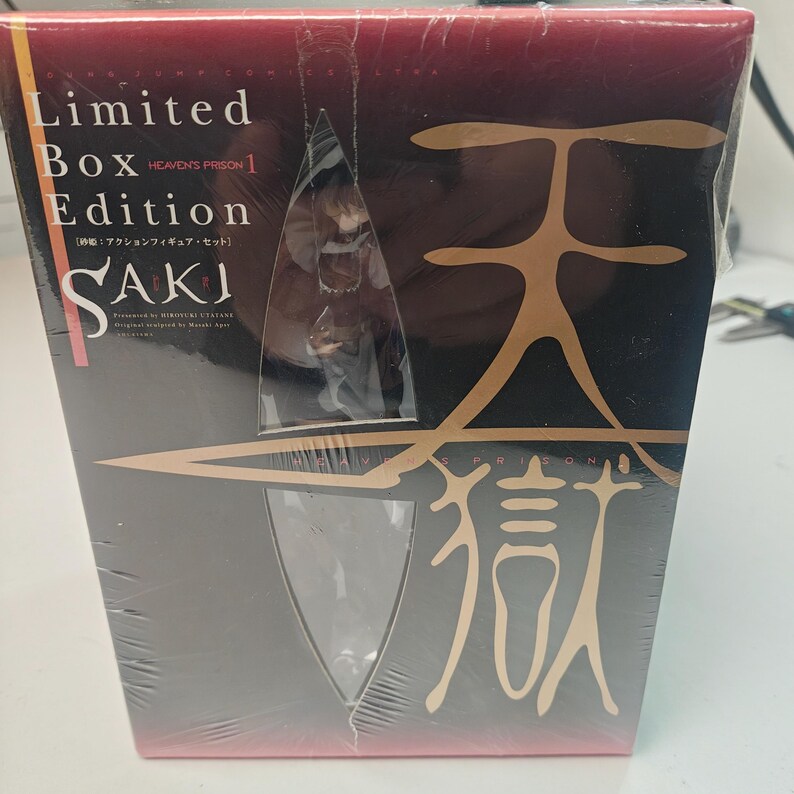 Puede incluir: Un set de figuras de acci&oacute;n SAKI de edici&oacute;n limitada en caja. La caja es principalmente negra con caracteres y texto japoneses dorados. La figura es visible a trav&eacute;s de una ventana de pl&aacute;stico transparente. La caja est&aacute; envuelta en pl&aacute;stico transparente.