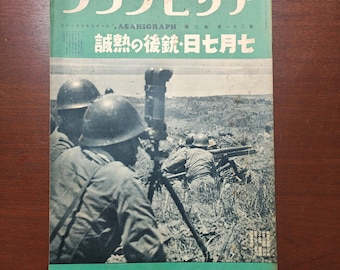 May include: Vintage Japanese magazine cover with green and white text, featuring a wartime scene with soldiers in helmets and military equipment. The cover has Japanese text and a photograph of soldiers in a field.