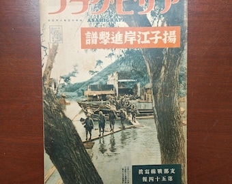 May include: Vintage Japanese magazine cover with Japanese text. The cover features a color illustration of soldiers on a river, with buildings in the background. The magazine title is in red and white, with additional text in a red rectangle.