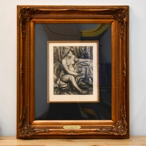 May include: A framed print of a seated nude figure, displayed within a larger ornate, gold-toned wooden frame. The artwork is a black and white sketch, showcasing a classical theme. The outer frame has detailed carvings.