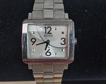 Relógio feminino Seiko LK Lukia, quadrado, em aço, quartzo, japonês, com numerais vermelhos.