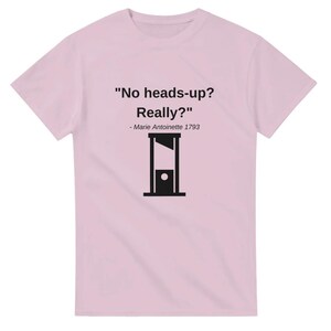 Może przedstawiać: Różowa koszulka z czarną sylwetką gilotyny i tekstem "Brak ostrzeżenia? Naprawdę?" - Maria Antonina 1793.