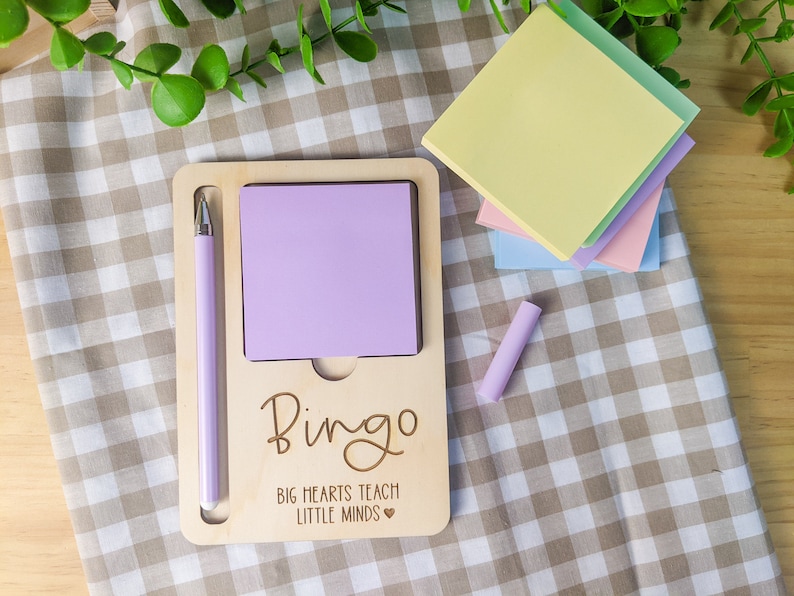 May include: A wooden desk organizer with a purple pen, a purple sticky note, and the text "Bingo Big Hearts Teach Little Minds".