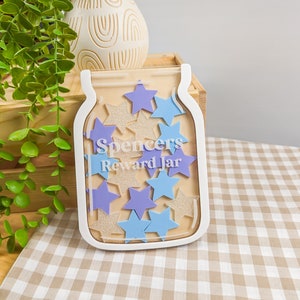 May include: White wooden jar with a clear plastic front, filled with blue and gold stars. The jar has the text "Spencers Reward Jar" on the front.