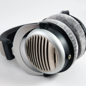 Puede incluir: Auriculares de diadema plateados y negros con almohadillas grises y el texto "DT 990" en el lateral.