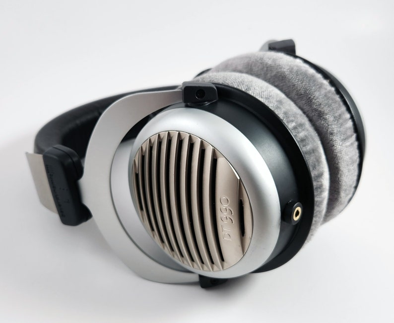 Puede incluir: Auriculares de diadema plateados y negros con almohadillas grises y el texto "DT 990" en el lateral.