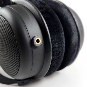 Puede incluir: Auriculares negros de diadema con un conector de audio dorado.