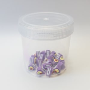 May include: A clear plastic container filled with small purple and white cake slices with a yellow and red topping.