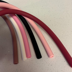 Op de afbeelding: Vijf verschillende gekleurde siliconen buizen, waaronder zwart, wit, roze, bruin en bordeaux.