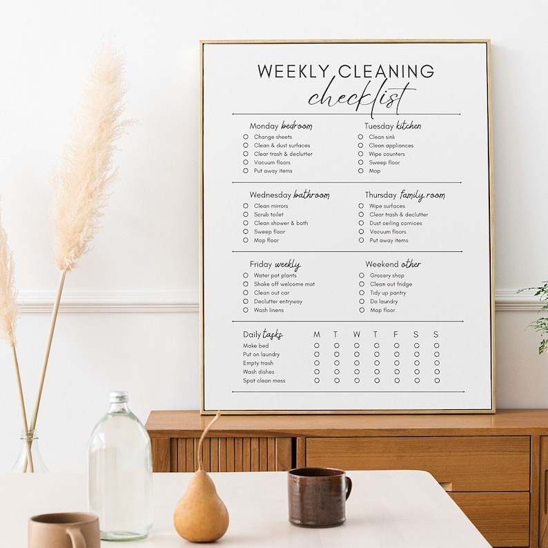Op de afbeelding: Een afdrukbare wekelijkse schoonmaakchecklist met een witte achtergrond en zwarte tekst. De checklist is onderverdeeld in dagelijkse, wekelijkse en weekendtaken. Elke dag van de week heeft een lijst met schoonmaaktaken voor verschillende delen van het huis, zoals de slaapkamer, badkamer, keuken en familiekamer.