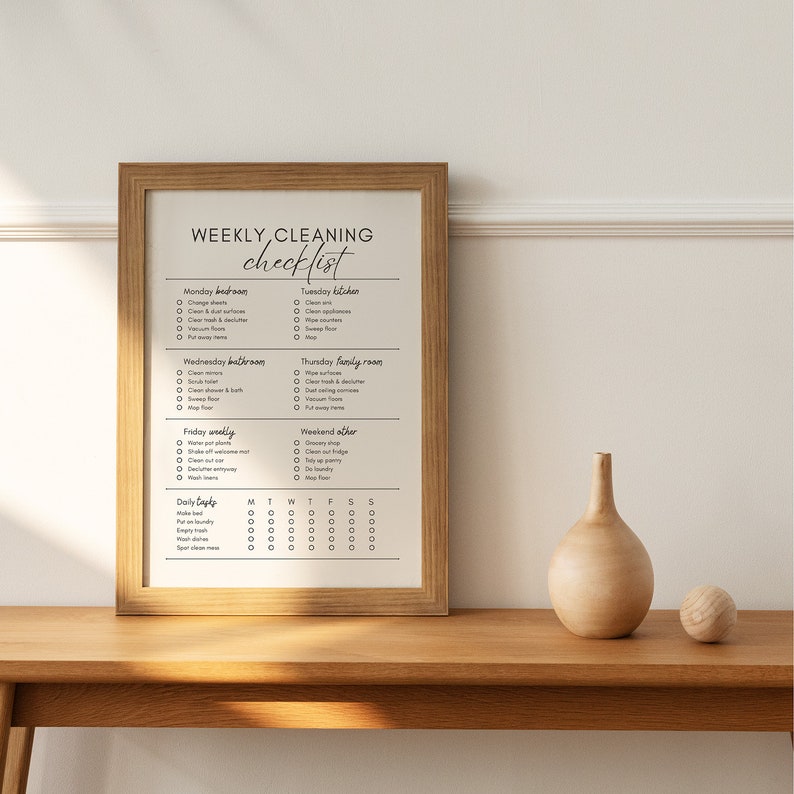 Op de afbeelding: Een afdrukbare wekelijkse schoonmaakchecklist met een kalenderrooster voor dagelijkse taken. De checklist bevat taken voor de slaapkamer, de keuken, de badkamer, de familiekamer en de weekendtaken.