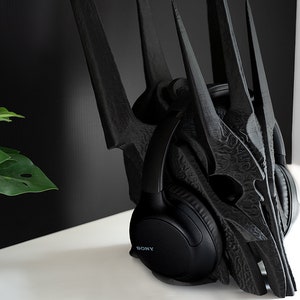 May include: Black headphones with the word "SONY" printed on the side, resting on a black, 3D printed crown-shaped object.