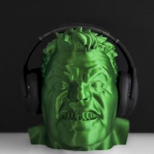 May include: A green 3D printed bust of a person wearing black headphones. The person has a serious expression with a furrowed brow and a slightly open mouth.