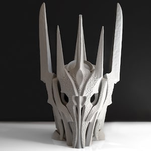 May include: A 3D printed model of a crown with a sharp, pointed design. The crown is made of a light gray plastic and has a detailed, intricate design.