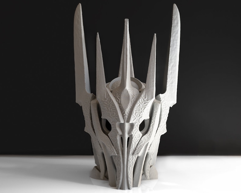 May include: A 3D printed model of a crown with a sharp, pointed design. The crown is made of a light gray plastic and has a detailed, intricate design.