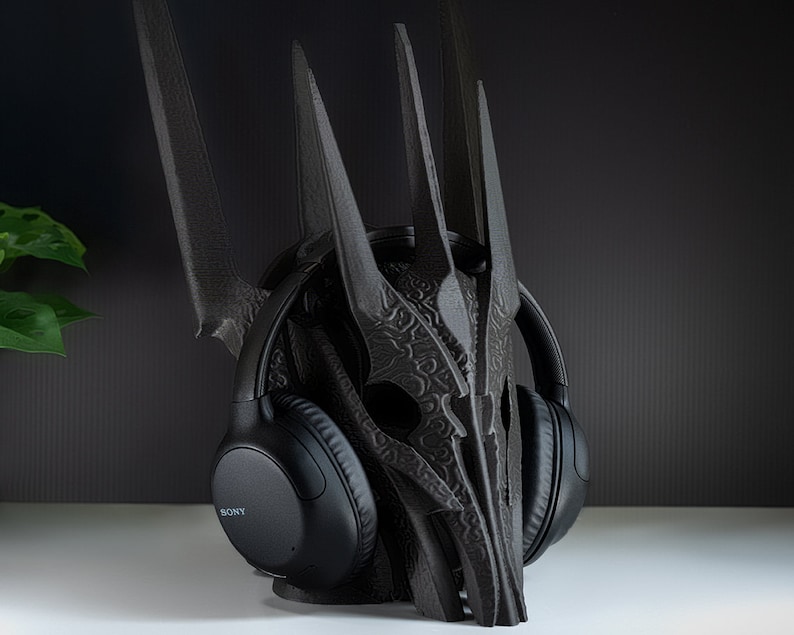 May include: Black headphones with the word "SONY" on the side, resting on a black, 3D printed stand shaped like a crown.