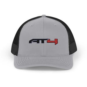 May include: A gray and black trucker hat with a red and black embroidered logo that says "AT4".