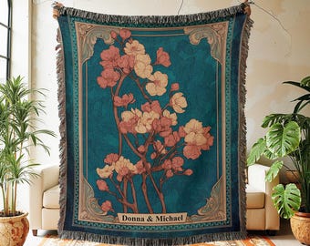 May include: A teal throw blanket with a floral design in shades of pink and cream. The blanket has a decorative border and fringe. The text "Donna & Michael" is displayed on the blanket. The text "@invenov Crafting Memories, One Gift at a Time." is also visible.