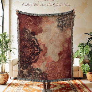 May include: A rectangular throw blanket with a floral pattern in burgundy, brown, and cream. The blanket has a fringed edge and is held up. The text "@invenov Crafting Memories, One Gift at a Time." is visible. The blanket is displayed indoors.
