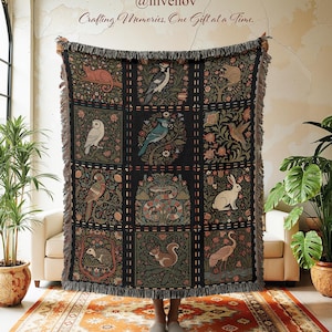 May include: A dark woven throw blanket with a repeating pattern of squares, each featuring a different animal and floral design. The blanket has a fringed edge and the text "Crafting Memories, One Gift at a Time."