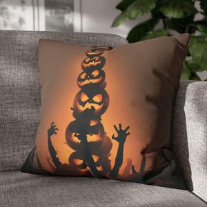 May include: A square throw pillow featuring a graphic print of a vertical stack of glowing orange jack-o'-lanterns against a dark background. Silhouettes of reaching hands and arms emerge from the bottom, surrounding the pumpkins in a spooky scene.