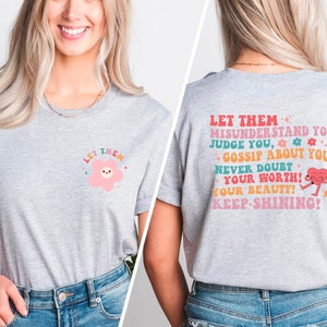 May include: Gray t-shirt with a pink flower graphic on the front and the text "LET THEM MISUNDERSTAND YOU, JUDGE YOU, GOSSIP ABOUT YOU, NEVER DOUBT YOUR WORTH! YOUR BEAUTY! KEEP-SHINING!" on the back.