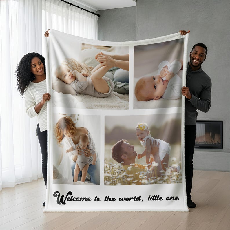 May include: A white fleece blanket featuring four photo collages of a baby. The blanket has the text "Welcome to the world, little one" in a black script font. The blanket is being held by a woman and a man.