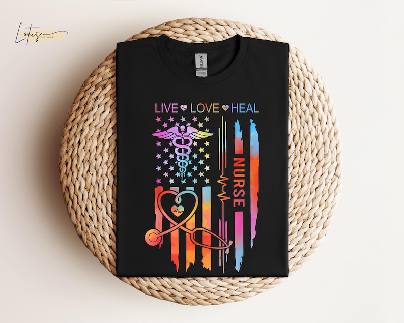 May include: A black t-shirt with a rainbow-colored American flag design. The flag has a medical caduceus symbol, a stethoscope, and the words 'Live Love Heal Nurse'.