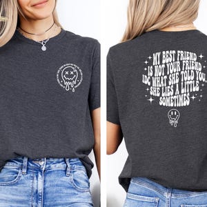 May include: A dark gray t-shirt with a white graphic on the front that says "My best friend is not your friend. IDC what she told you. She lies a little sometimes." and a white smiley face with an X for eyes on the back.