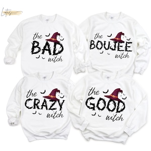 May include: Four white long-sleeve crewneck sweatshirts featuring black text and a purple witch hat graphic. The shirts display the phrases: the BAD witch, the BOUJEE witch, the CRAZY witch, and the GOOD witch, each accented with small black bats.