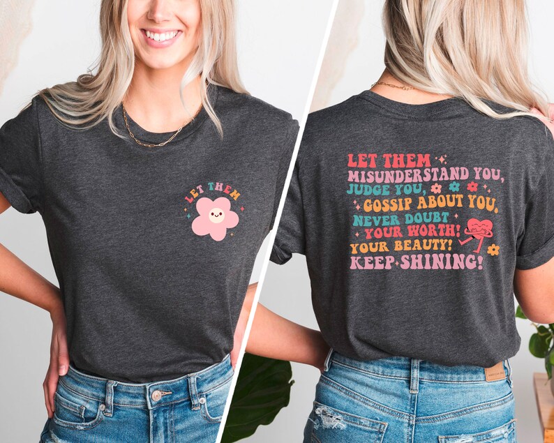 May include: A dark gray t-shirt with a pink flower graphic on the front and the text "LET THEM MISUNDERSTAND YOU, JUDGE YOU, GOSSIP ABOUT YOU, NEVER DOUBT YOUR WORTH! YOUR BEAUTY! KEEP SHINING!" on the back.