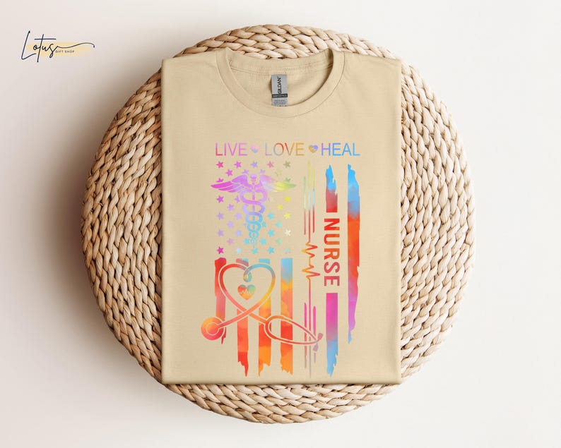 May include: A beige t-shirt with a rainbow-colored American flag design. The flag has a stethoscope and the words "Live Love Heal Nurse" on it.
