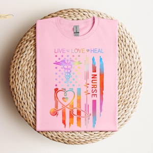 May include: Pink t-shirt with a rainbow design featuring a stethoscope, a caduceus, and the words "Live Love Heal Nurse".