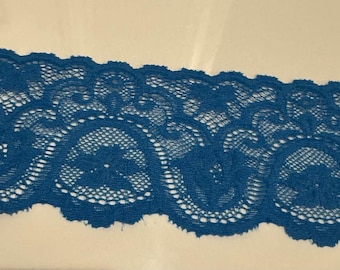May include: Close-up of a strip of teal lace. The lace features a detailed floral pattern with a scalloped edge. The intricate design is visible against a neutral background, highlighting the delicate texture and color.