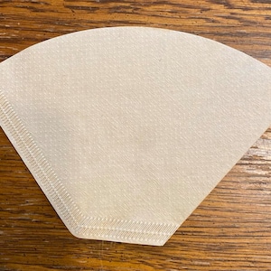 May include: A white paper coffee filter with a scalloped edge.