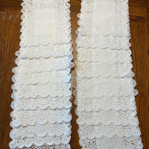 May include: Two stacks of white paper doilies with a delicate lace pattern. Each stack contains 10 doilies.